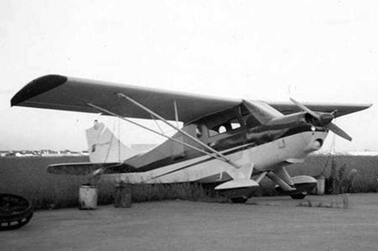 7KC-Olympia parked on a weedy ramp. BW photo.